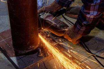 While grinding iron worker cuts metal with an abrasive disk sparks