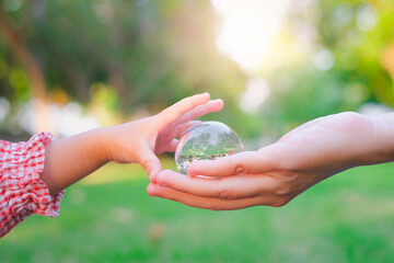 Adult person passes crystal ball to baby hand a healthy ecology to a new generation. Healthy...