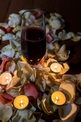 Obraz na płótnie Canvas Wine glass with rose petals and candles 