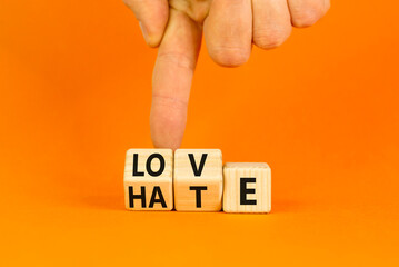 From hate to love symbol. Turned wooden cubes and changed the word hate to love. Beautiful orange table, orange background, copy space. Businessman hand. Valentines day and hate or love concept. - obrazy, fototapety, plakaty
