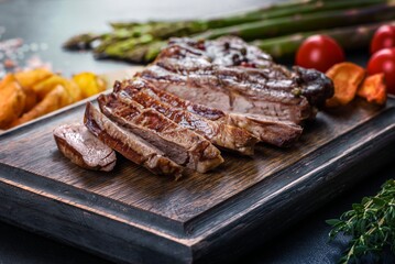 Delicious juicy fresh beef steak with spices and herbs on a dark concrete background