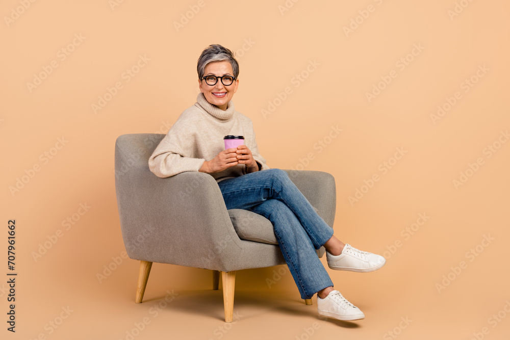 Canvas Prints Full body photo of mature age lady in jeans and turtleneck loves winter vibes drinking coffee at cafe isolated on beige color background