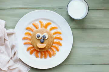 Fun, colorful creative pancake sun for children with banana and blueberry eyes and oranges for sunbeams and smile to encourage kids to eat healthy foods.