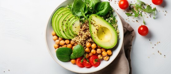 Top view vegetable salad with quinoa, avocado, tomato, spinach, and chickpeas - on white table.