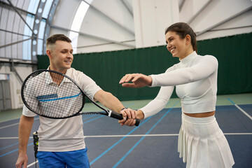 Confident man teaching woman to properly hold paddle racquet during training