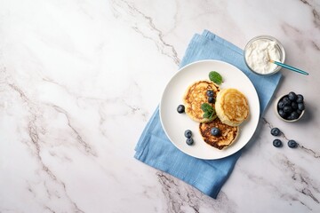 Cottage cheese pancakes served with curd and blueberries, top view flat lay on marble background,...