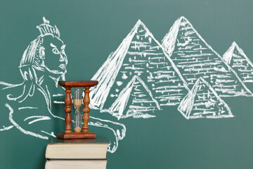 Books and an hourglass against the background of the Egyptian pyramids and the Sphinx drawn with...