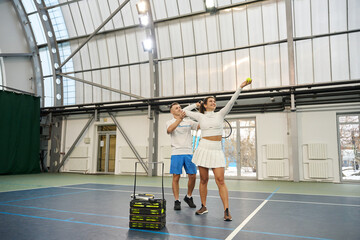 Obraz premium Man instructor concentrates on teaching serving technique to woman tennis player