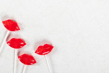 Lollipops in the shape of red lips on paper sticks. Isomalt lollipops. White background. Top view. Copy space