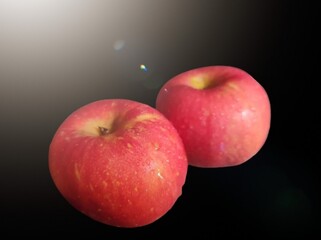 Two fresh apples isolated on the black background, with lamp light. 