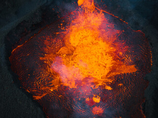 Erupting volcano, red hot boiling lava pouring out of crater into the devastated surrounding area,...