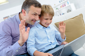 Man and child waving on computer video chat