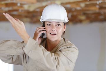 indignant female builder gesticulating while on telephone