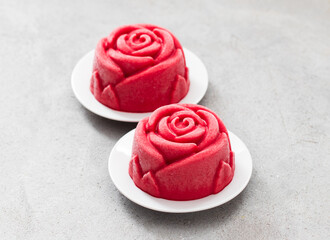 Vegan dessert. Strawberry ice cream in the shape of a red rose. Couple. On a plate. Light grey background. Close-up