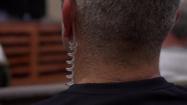A security guy wearing an earpiece at an indoor event