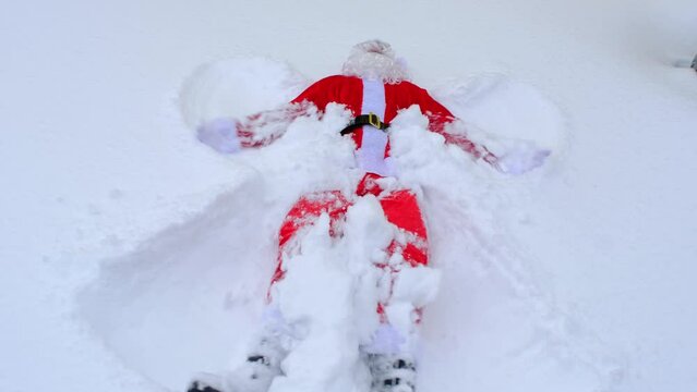 Santa Claus makes snow angels in the snow. Humor, winter fun, Santa is tired and drunk