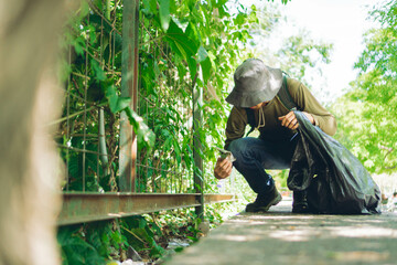 young Latin man picking up garbage from a park ecological reserve, copy space