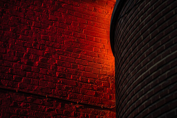 Le soleil illumine un pan de mur de briques peintes en rouge - obrazy, fototapety, plakaty