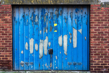 porte de garage fermée bleue et décrépie