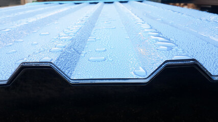 Blue corrugated sheet with drops of water. Close-up