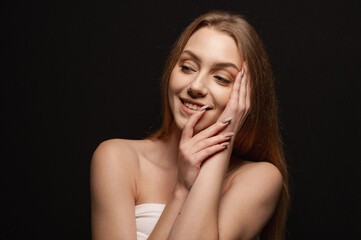 Naklejka premium Beatiful portrait of a beautiful and gentle blonde girl on an isolated black background. Skin care