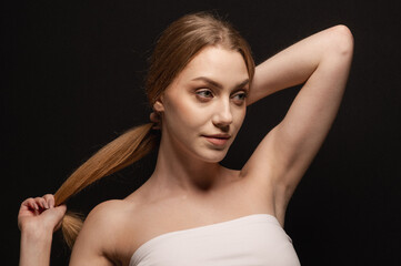 Beatiful portrait of a beautiful and gentle blonde girl on an isolated black background. Skin care