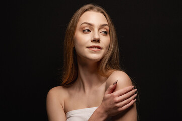 Fototapeta premium Beauty portrait of a beautiful blonde girl on an isolated black background. Skin care