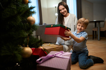 Woman celebrating Christmas with her son sharing presents X-mas tree in hotel