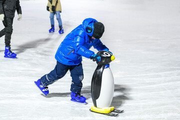 Cherepovets, Russia, January 7, 2024, Boy in warm clothes  learning ice skating with helper on ice...