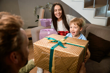 Man giving present to his little son while celebrating Christmas holiday