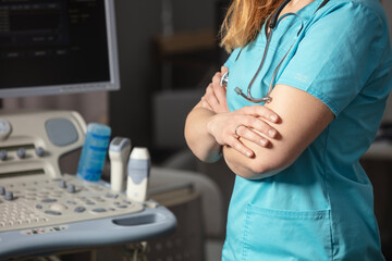 Female doctor woman in uniform  in a hospital near the  ultrasound diagnostic machine equipment and ready to examine patients and do ultrasound of heart, thyroid gland or abdominal cavity. Close up.