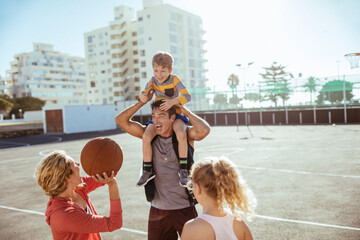 Happy family having fun with basketball on outdoor court