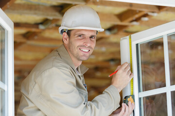 Naklejka na ściany i meble worker using tape measure window in construction site