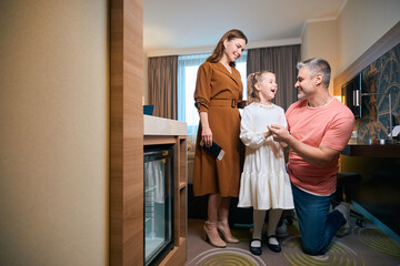 Obraz premium Happy caucasian family of mother, father and daughter in hotel room