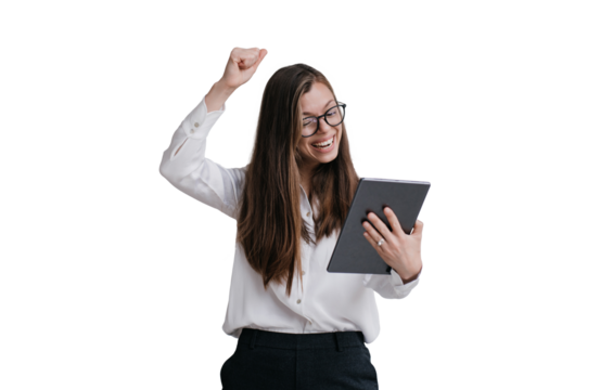 Expressive young brunette businesswoman in glasses, white shirt and black pants holding tablet making video call rising fist up against transparent background, celebrating great deal, laughing