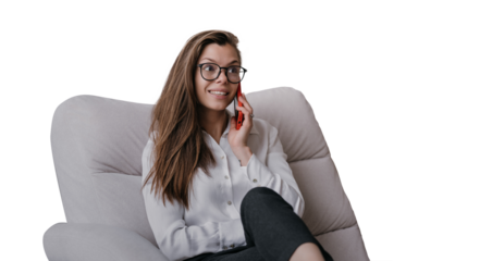 Amazed young businesswoman in glasses, sitting in chair talking by cell phone smiling with surprised face against transparent background. Successful woman gets great news. Business