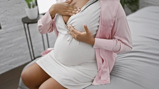 Expecting hispanic woman's morning ritual, examining her breast in bedroom while resting on bed