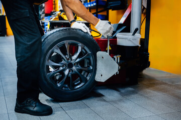 Close-up of a mechanic holding a tire changing device To change new tires. - obrazy, fototapety, plakaty