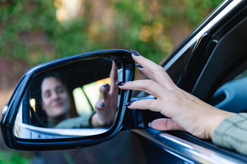 Hand of woman driver adjusting the side view mirror of her car. Selective focus. Transportation, travel and road safety concepts - obrazy, fototapety, plakaty