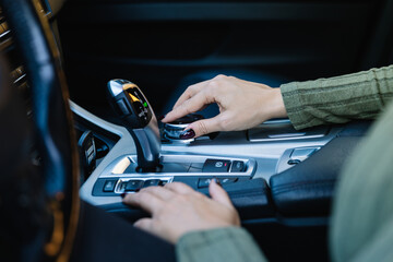 Close up of female hand operating the on-board computer joystick of her high-end automatic car. Driving concept and vehicle equipment