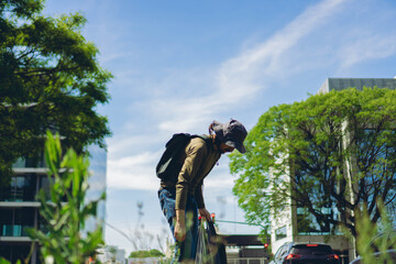 young Latin man cleans garbage from the city's green areas with a garbage bag. low angle view