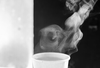 The movement of steam over the disposable paper cup. Black and white. Copy space.