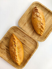 Delicious sweet ruddy small pie on square wooden bamboo plate. Two serving of fresh pastries, sprinkled with sugar. Top view.