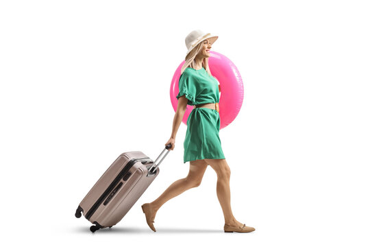 Full length profile shot of ayoung lady with a suitcase walking and carrying a swimming ring