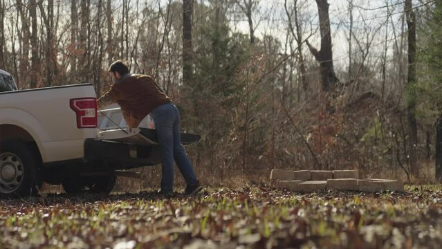 Man unloading bricks from a pickup truck and building an outdoor fire pit