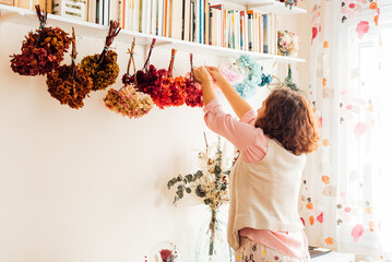 Unrecognizable female specialist hanging bouquets up in store