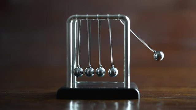 Metal Newton cradle placed on wooden background as representation of momentum concept, cradle balance steel balls, school teaching supplies, desk toy, gifts home decoration