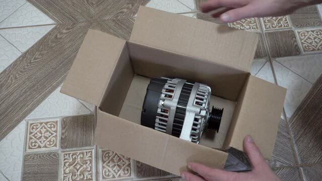 a new generator for the car, a man opened a box with a new generator, a generator to generate electricity in a car, new car parts