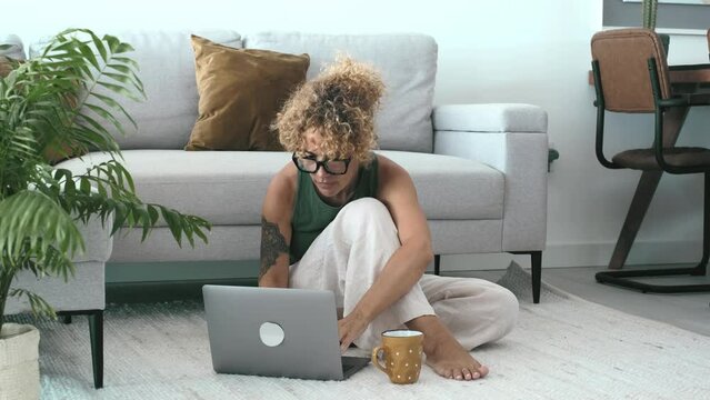 One woman using laptop computer sitting on the floor at home in modern indoor leisure activity alone. Smart working and searching on web concept people lifestyle. Trendy female use notebook indoor