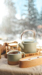 Cozy winter home interior, candle, tea and teapot on the windowsill